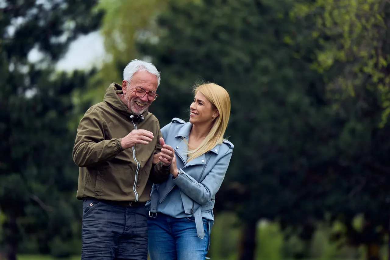 Senior und junge Frau unterhalten sich lachend im Freien