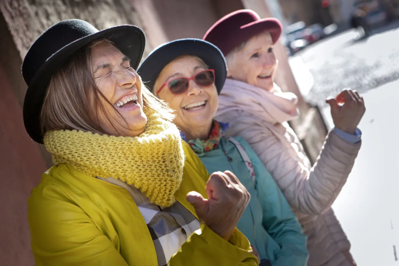 Drei Frauen lachen gemeinsam draußen in der Sonne