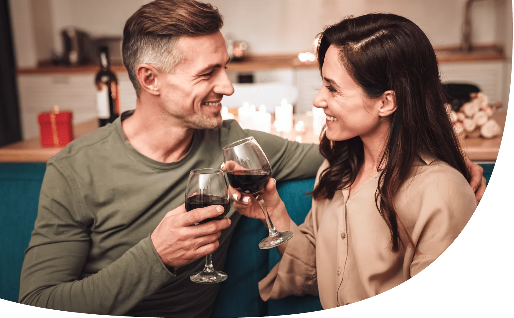 Ein junges Paar sitzt auf der Couch und stößt mit Rotwein an