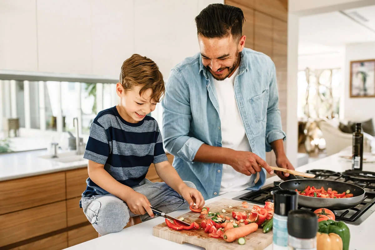 Ein Vater ist mit seinem Sohn in der Küche und bereitet das Mittagessen zu