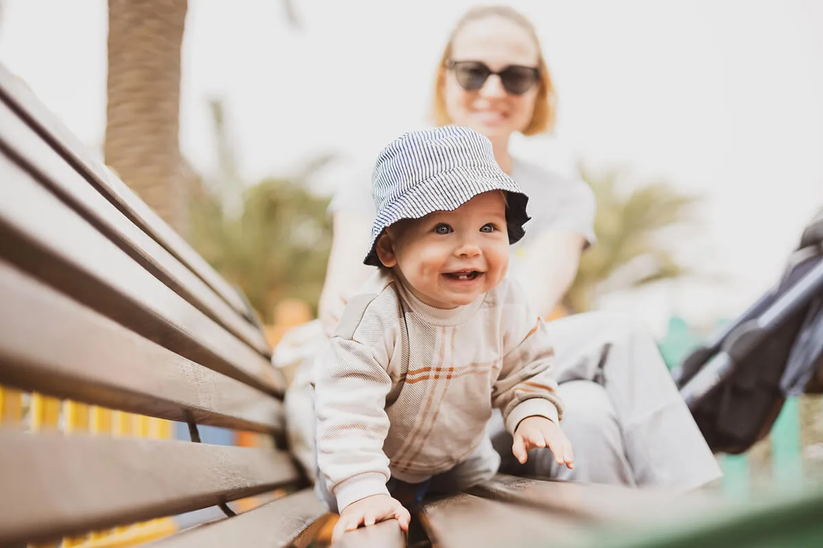 Mutter ist mit Baby draußen und sitzt auf einer Bank