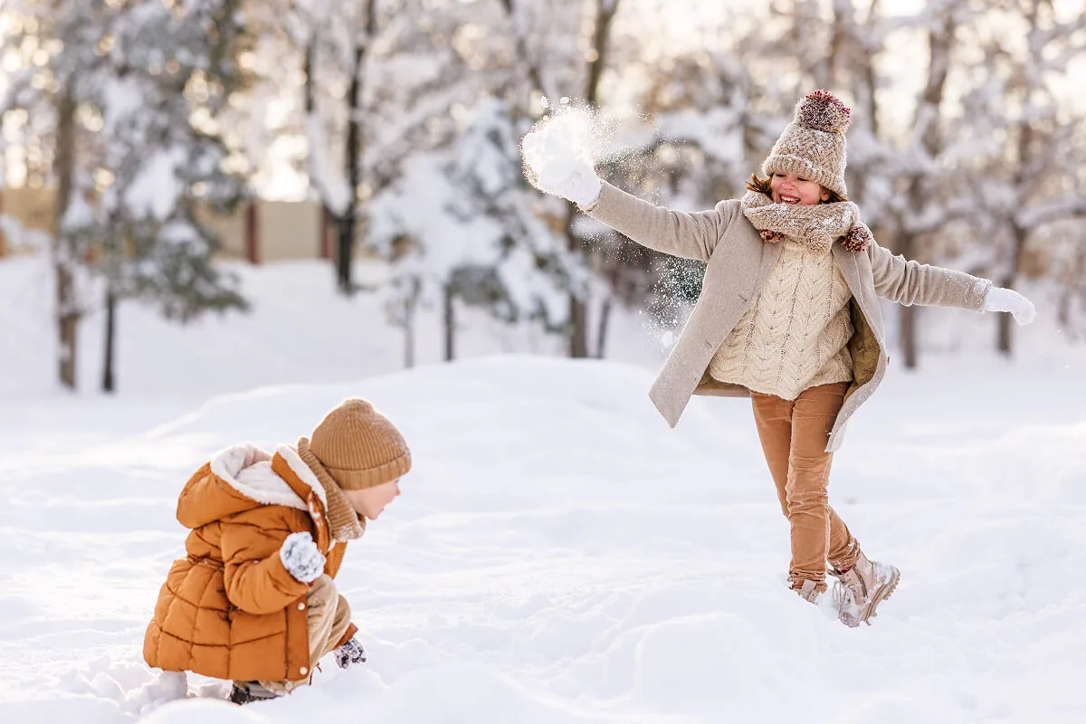 Zwei Kinder machen eine Schneeballschlacht und spielen im Schnee