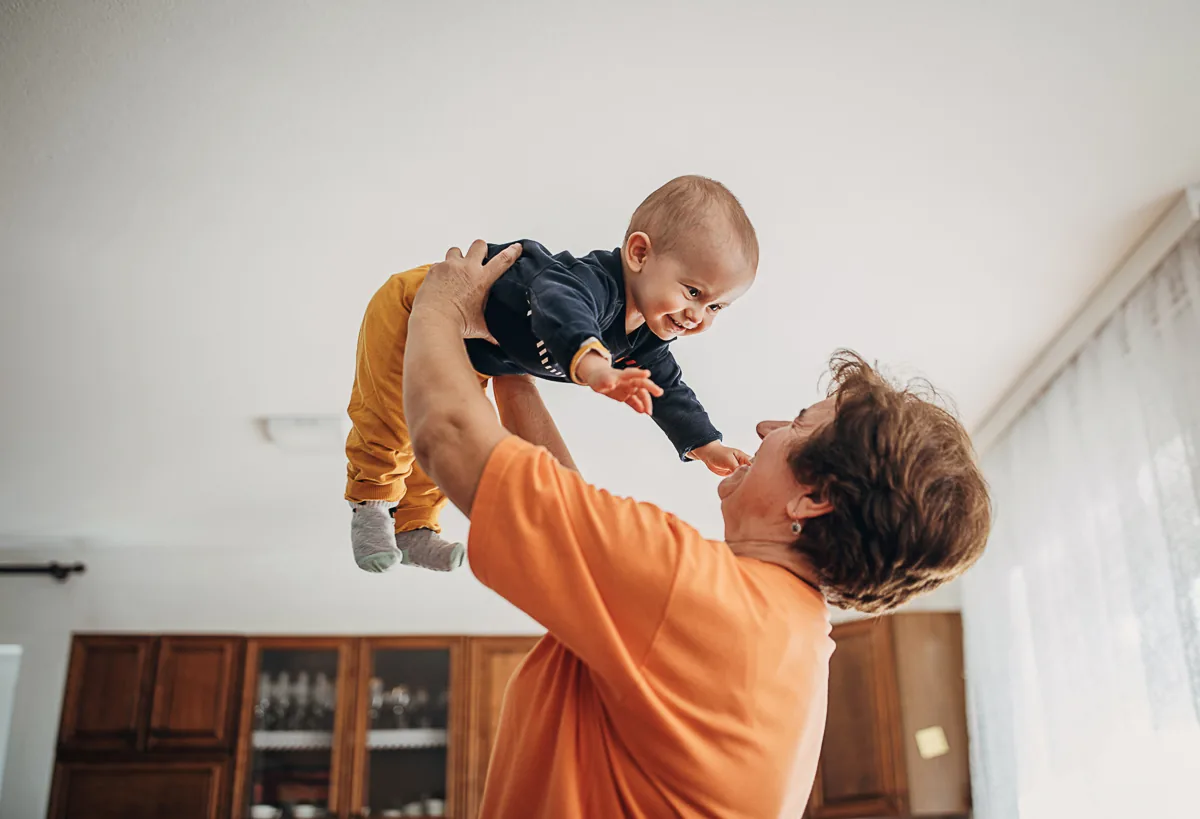 Eine glückliche Leihoma hat einen schönen und lustigen Moment mit dem zu betreuenden Baby