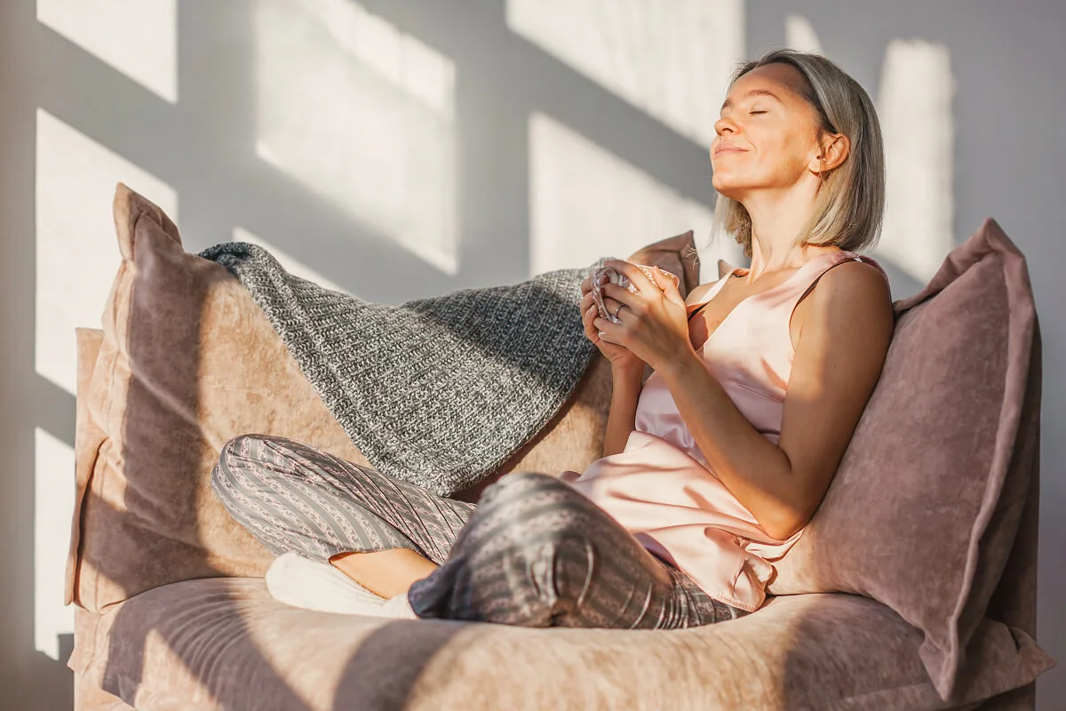 Eine entspannte Frau sitzt auf der Couch und relaxt