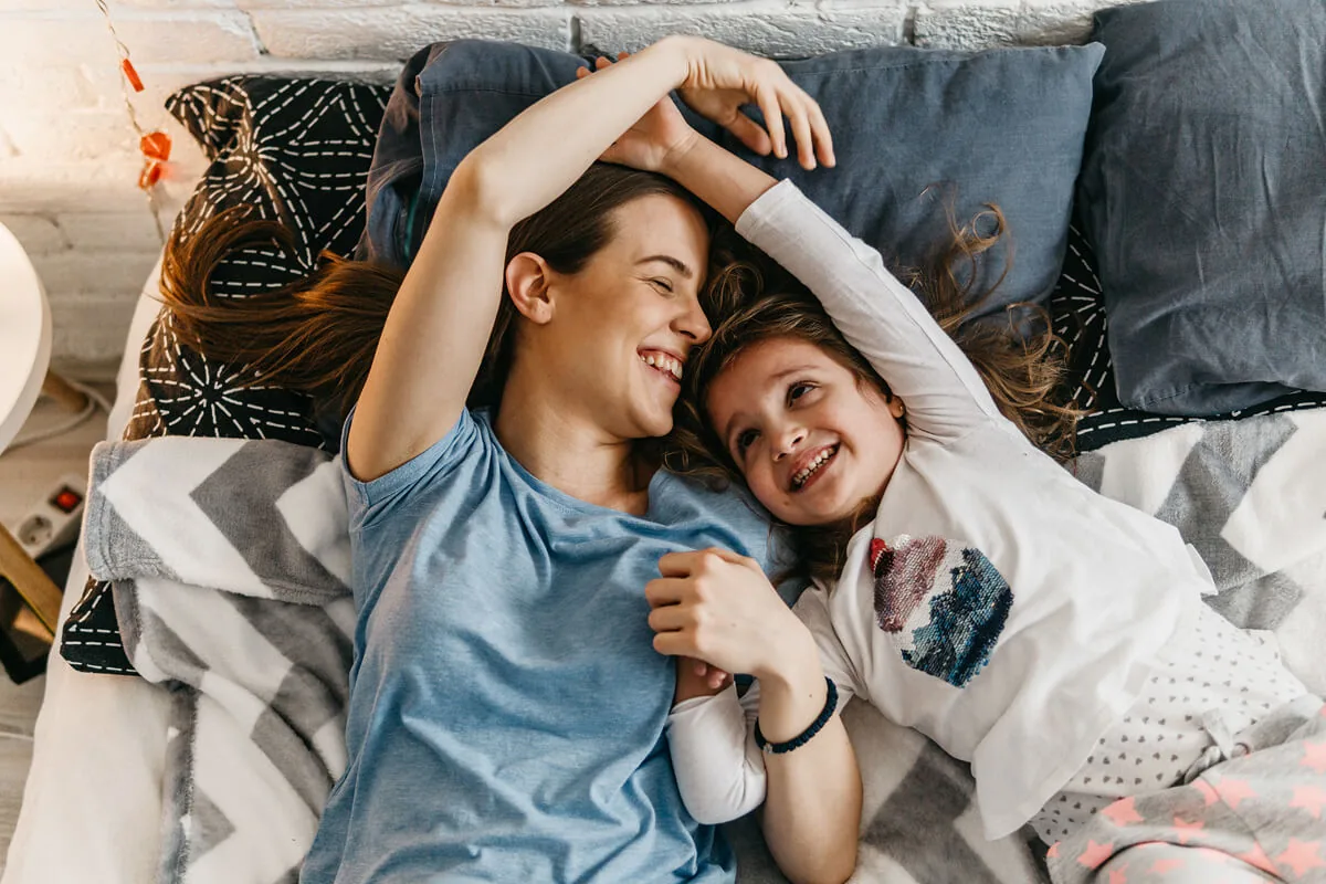 Ein Babysitter liegt mit Kind im Bett